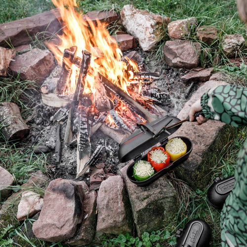 Cast iron potato cooker with hinged lid cooking stuffed bell peppers over an open campfire, ideal for Farm, Garden & Tool, Camping, Best Sellers, and Promo Eligible collections.