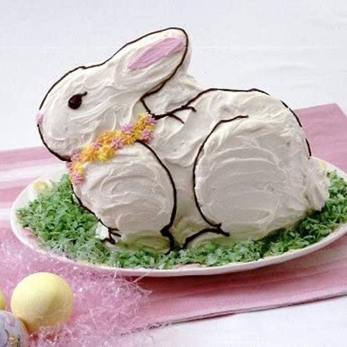 Frosted bunny-shaped cake decorated with piped icing flowers on a white platter with green shredded garnish, ideal for Kitchen & Food, Baking Supplies, USA Made, and Best Sellers collections.