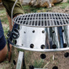 Stainless steel replacement grilling grate with a 13.4-inch diameter set on a portable outdoor grill, perfect for camping, backyard grilling, and Farm, Garden & Tool collections.