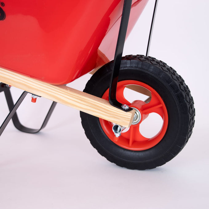 Close-up of the bright red wheel and natural hardwood handle on a handcrafted Eli & Mattie Kids Wheelbarrow, designed for outdoor play in children's toys and garden collections.