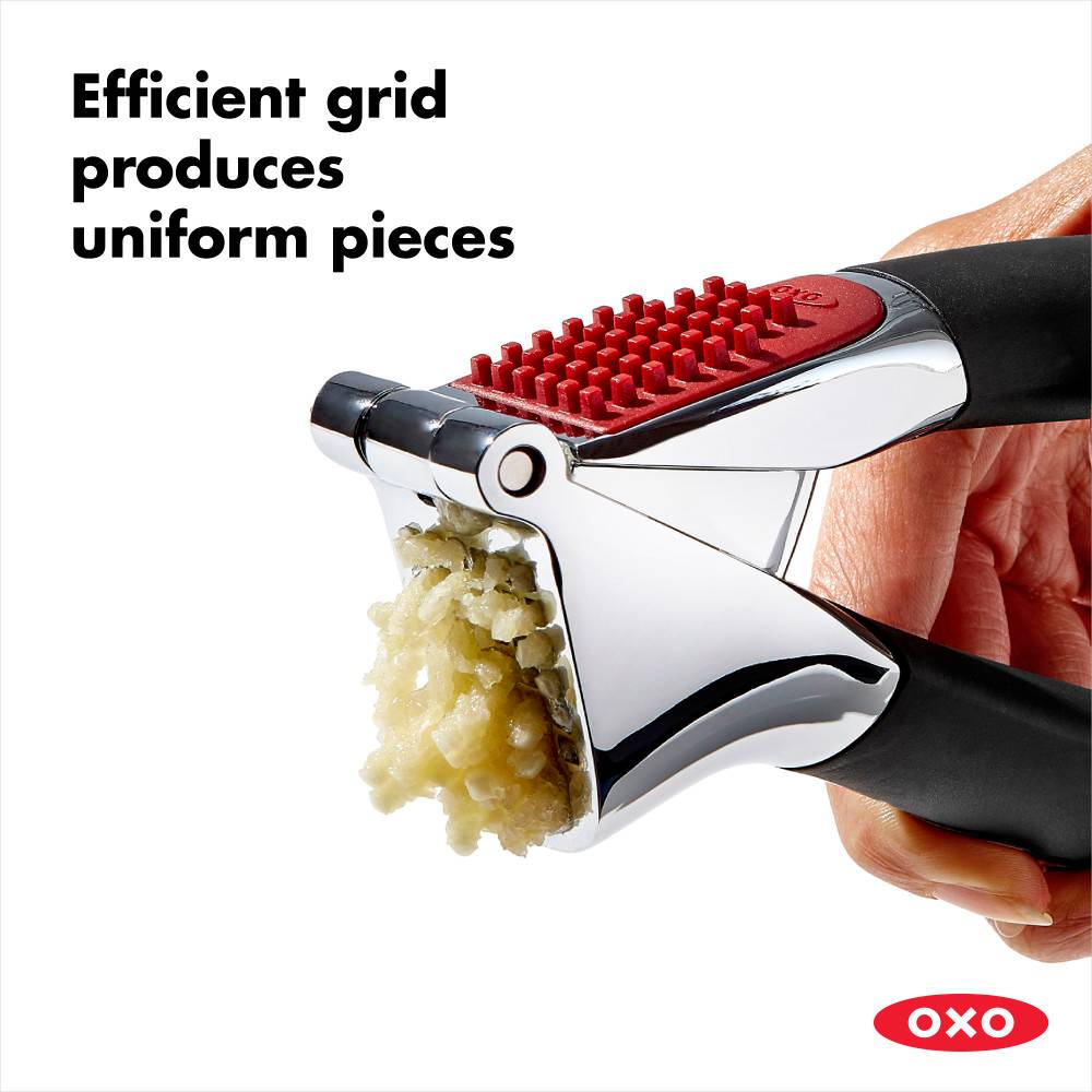 Handheld garlic press with a sturdy stainless steel chamber and soft, black non-slip handles crushing garlic into uniform pieces, perfect for Kitchen & Food and Cooking Helpers collections.