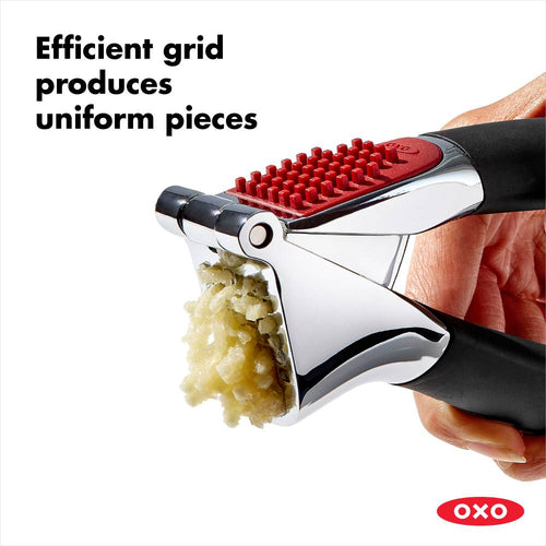 Handheld garlic press with a sturdy stainless steel chamber and soft, black non-slip handles crushing garlic into uniform pieces, perfect for Kitchen & Food and Cooking Helpers collections.