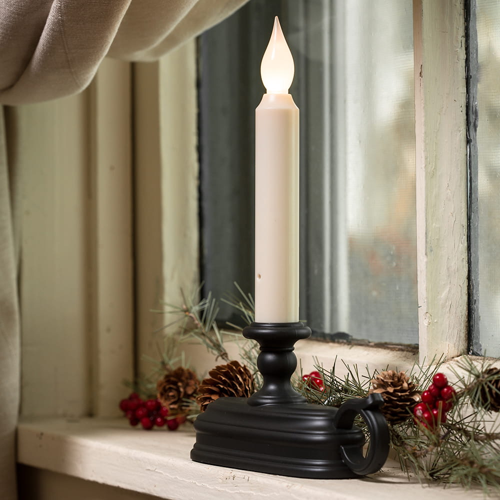 LED candle with warm white flame in a black metal holder on a window sill decorated with pinecones and red berries, perfect for Home & Decor and Holiday Hosting collections.