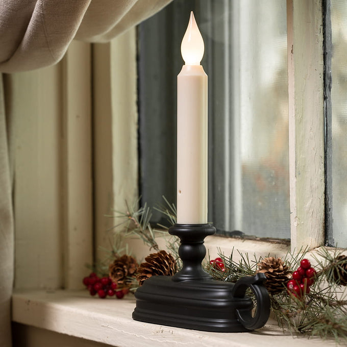 LED candle with warm white flame in a black metal holder on a window sill decorated with pinecones and red berries, perfect for Home & Decor and Holiday Hosting collections.