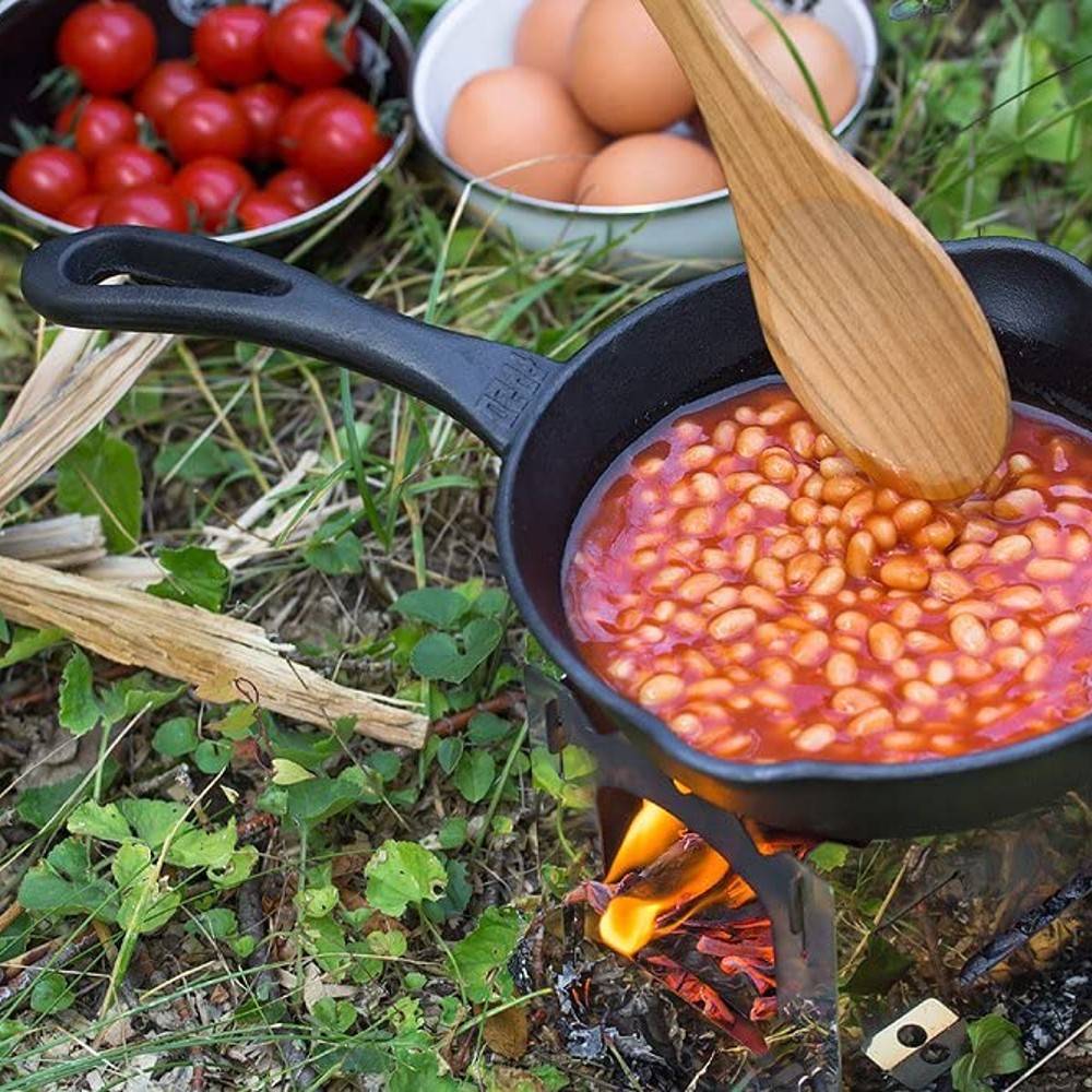 Black cast iron skillet with long handle cooking baked beans over an open fire outdoors, surrounded by fresh eggs and cherry tomatoes, ideal for Farm, Garden & Tool, Camping, Kitchen & Food, Cookware, Cast Iron, and Best Sellers collections.