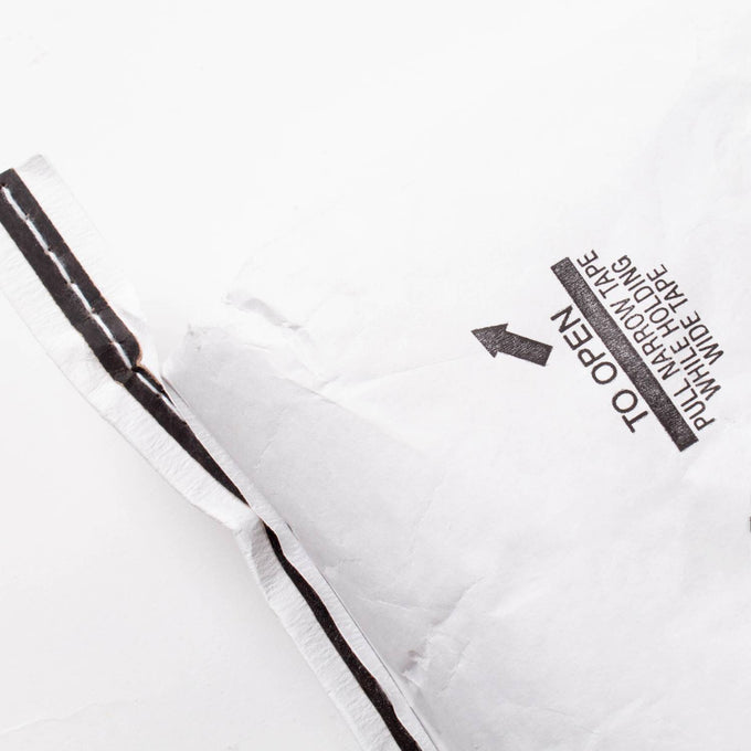 Partial view of a large white paper bag with printed opening instructions and black tape, used for packaging organic whole amaranth grain in Farm, Garden & Tool and Pantry collections.