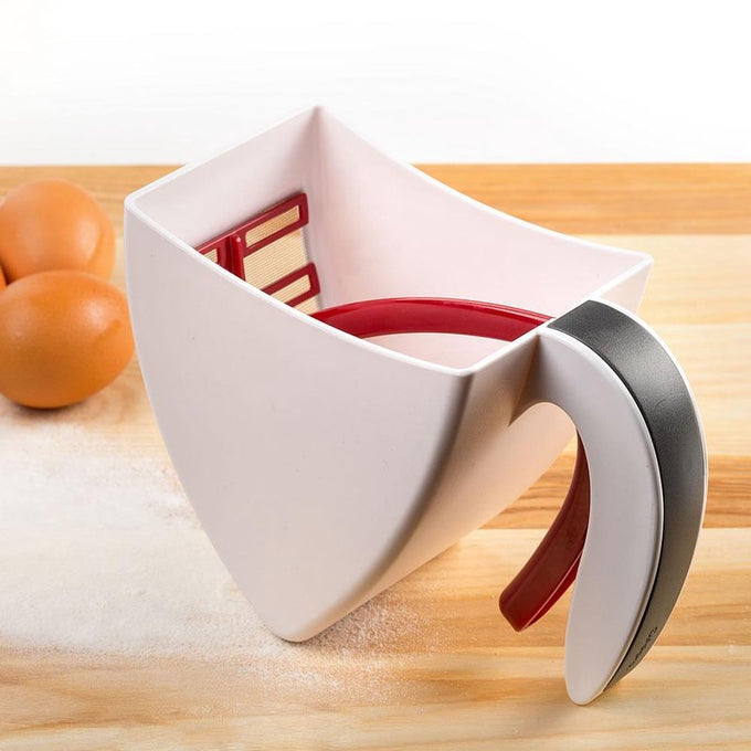 White durable plastic scoop and sift flour sifter with ergonomic handle and red trigger, designed for clump-free baking, shown on wooden surface with eggs nearby in Kitchen & Food collections.