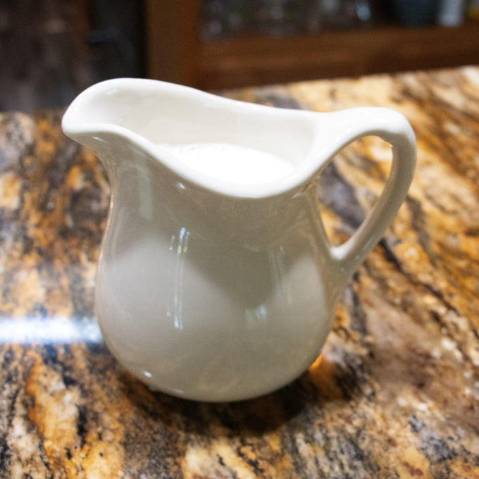 Handcrafted cream-colored stoneware pitcher with a classic shape, made in the USA, designed for serving in Kitchen & Food, Dinnerware, Storage and Serving, and Best Sellers collections.