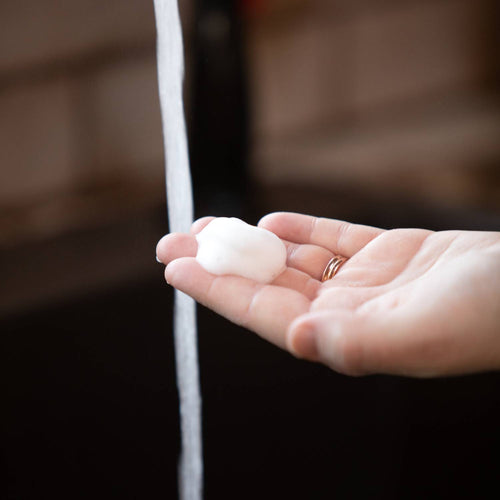 Hand holding rich foam from Lehman's handcrafted moisturizing foaming soap beneath running water, highlighting its natural oils and gentle cleansing in Health & Wellness and Soaps collections.