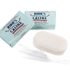 Three-pack of fragrance-free bar soaps in light blue wrappers and one unwrapped creamy white bar resting on a white cloth, made in USA for sensitive skin in Health & Wellness and Grooming collections.