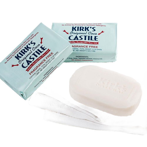 Three-pack of fragrance-free bar soaps in light blue wrappers and one unwrapped creamy white bar resting on a white cloth, made in USA for sensitive skin in Health & Wellness and Grooming collections.