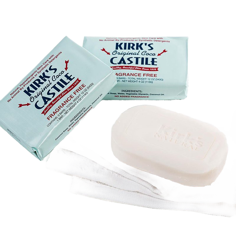 Three-pack of fragrance-free bar soaps in light blue wrappers and one unwrapped creamy white bar resting on a white cloth, made in USA for sensitive skin in Health & Wellness and Grooming collections.