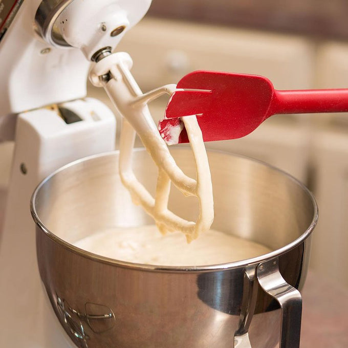 Red flexible silicone spatula scraping batter from a metal mixer beater over a stainless steel mixing bowl, suitable for Kitchen & Food, Kitchen Gadgets, Cooking and Baking Helpers, Best Sellers, and Promo Eligible collections.