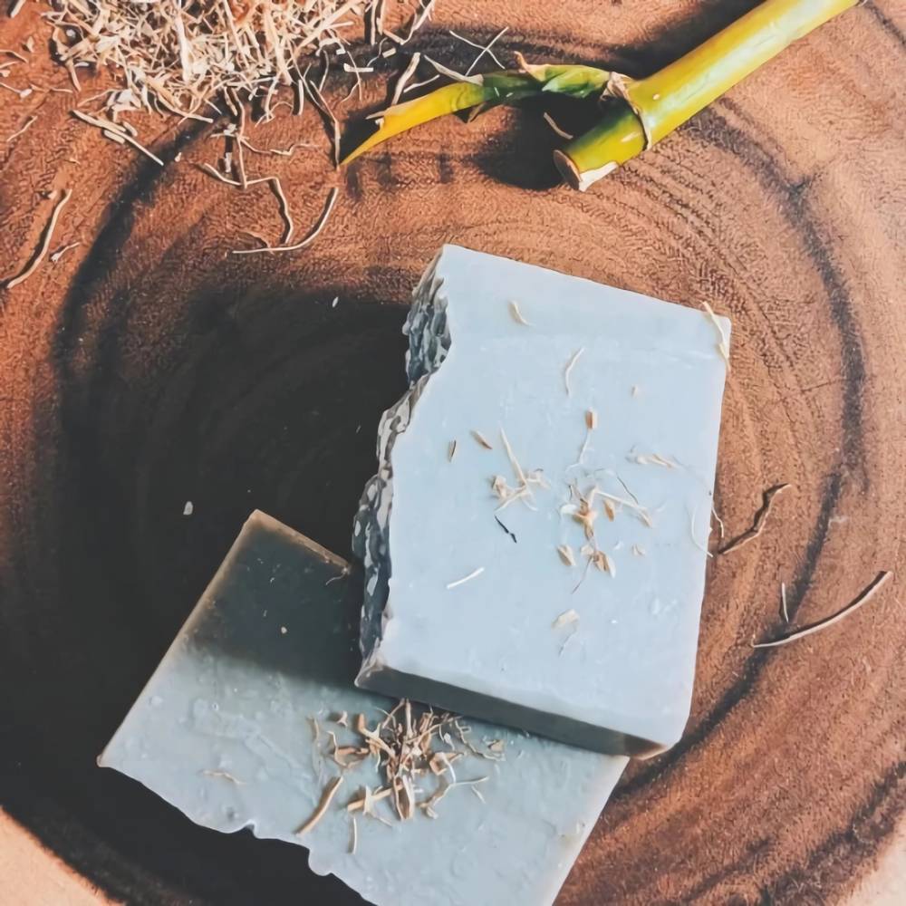 Two handmade vetiver infused soap bars with natural wood shavings on a round wooden surface, highlighting organic ingredients in Health & Wellness, Soaps collections.
