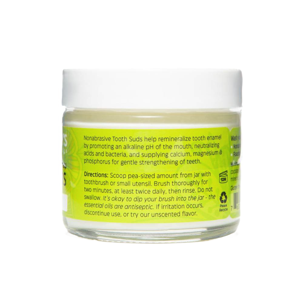 Clear jar of peppermint brushing soap tooth suds with bright green label detailing nonabrasive, enamel-strengthening formula, part of USA made health and wellness grooming collection.