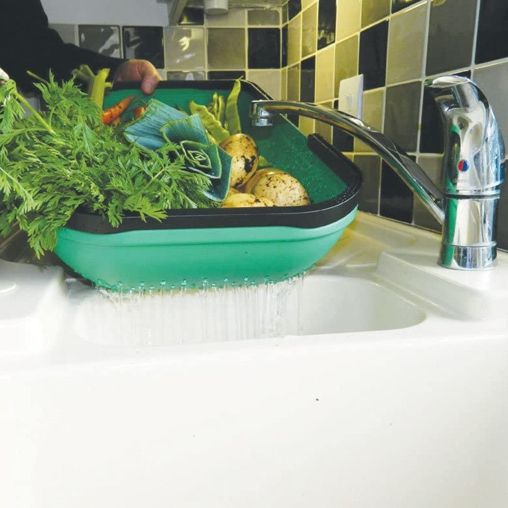Green colander trug with carry handles draining fresh garden vegetables under running kitchen faucet, a practical tool featured in Farm, Garden & Tool and Garden Accessories collections.