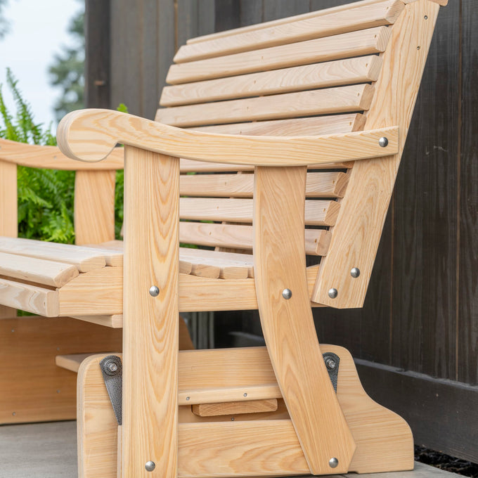 Close-up of a handcrafted cypress wooden glider swing with contoured back and curved armrests, showcasing natural wood grain and durable Amish-made outdoor furniture design.