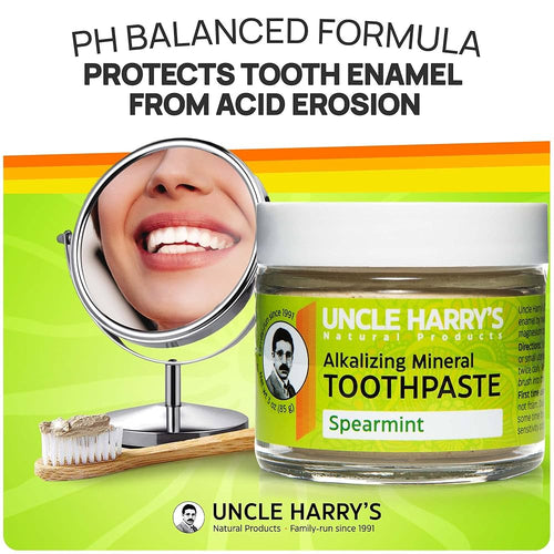 Handcrafted glass jar of spearmint alkalizing mineral toothpaste with a white lid and bright yellow label, shown with a wooden toothbrush and a mirror reflecting a smiling mouth, promoting Health & Wellness, Grooming and Personal Hygiene, USA Made, Best Sellers, and Promo Eligible collections.