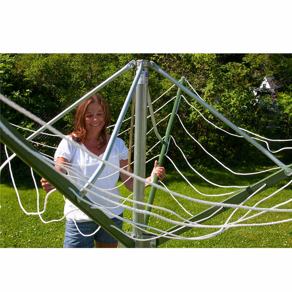 Woman adjusting a large handcrafted rotating clothes dryer with green canvas and metal frame in a sunny backyard, perfect for Home & Decor, Laundry Supplies, and Clothesline Accessories collections.