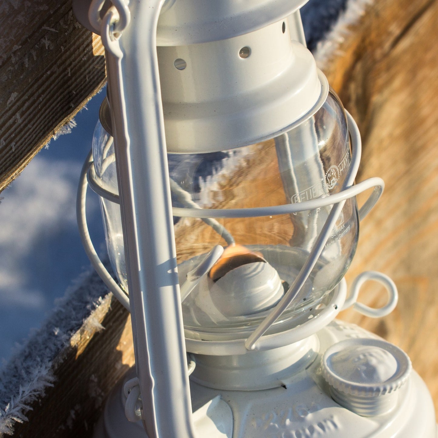 Clear glass replacement globe fitted on a white lantern, designed to provide bright flame visibility, ideal for camping, emergency supplies, and outdoor lighting needs.