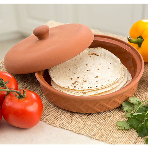 Terra cotta tortilla warmer with lid slightly ajar, holding warm tortillas, displayed with fresh tomatoes, yellow bell pepper, and cilantro on a woven placemat, part of Kitchen & Food, Storage and Serving, Best Sellers, and Promo Eligible collections.