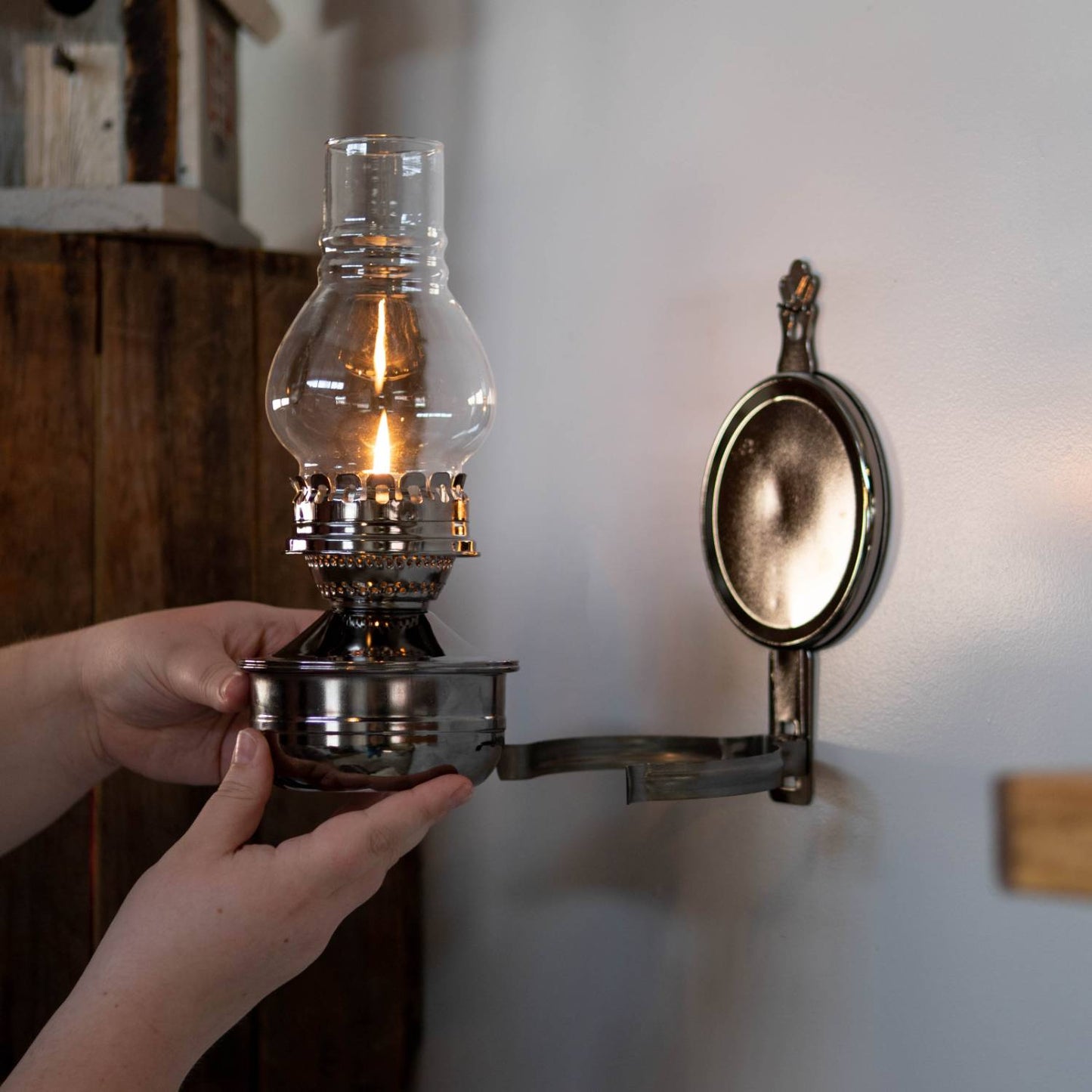 Handcrafted woodshed wall lamp with a painted pewter-like finish, clear ribbed glass chimney, and round reflector, featuring warm, ambient light for cozy spaces in Lamps & Lighting and Oil Lamps collections.