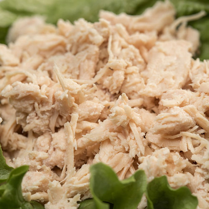 Close-up of shredded cooked chicken resting on fresh green lettuce, representing a hearty meal option from Kitchen & Food, Food, Meats, Best Sellers, and Promo Eligible collections.
