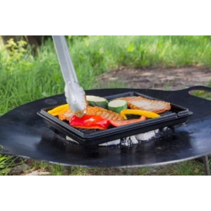 Square cast iron griddle pan with ridges grilling colorful vegetables and meat over an outdoor fire pit, ideal for farm, garden, camping, kitchen, cookware, and cast iron collections.
