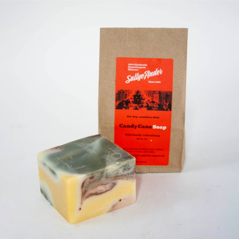 Handcrafted hypoallergenic Candy Cane soap bar with creamy yellow, green, and brown swirls, paired with eco-friendly kraft paper packaging featuring a bright red label, made in USA for Health & Wellness, Grooming and Personal Hygiene, Soaps, and Best Sellers collections.