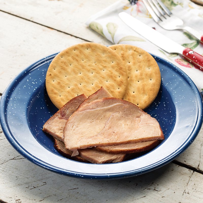 Blue enamelware plate holding several slices of smoked ham alongside round saltine crackers on a rustic white wooden surface, suitable for Farm, Garden & Tool, Kitchen & Food, Emergency Supplies, Freeze Dried, and USA Made collections.
