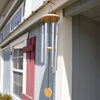 Handcrafted hand-tuned silver metal windchime with natural wood circular windcatcher hanging on a farmhouse exterior, ideal for farm, garden accessories, and best sellers collections.