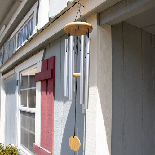 Handcrafted hand-tuned silver metal windchime with natural wood circular windcatcher hanging on a farmhouse exterior, ideal for farm, garden accessories, and best sellers collections.