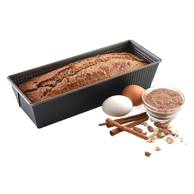 Rectangular heavy gauge steel loaf pan with nonstick textured surface showing baked bread inside, accompanied by eggs, cinnamon sticks, nuts, and a small bowl of brown flour for Kitchen & Food and Baking Supplies collections.