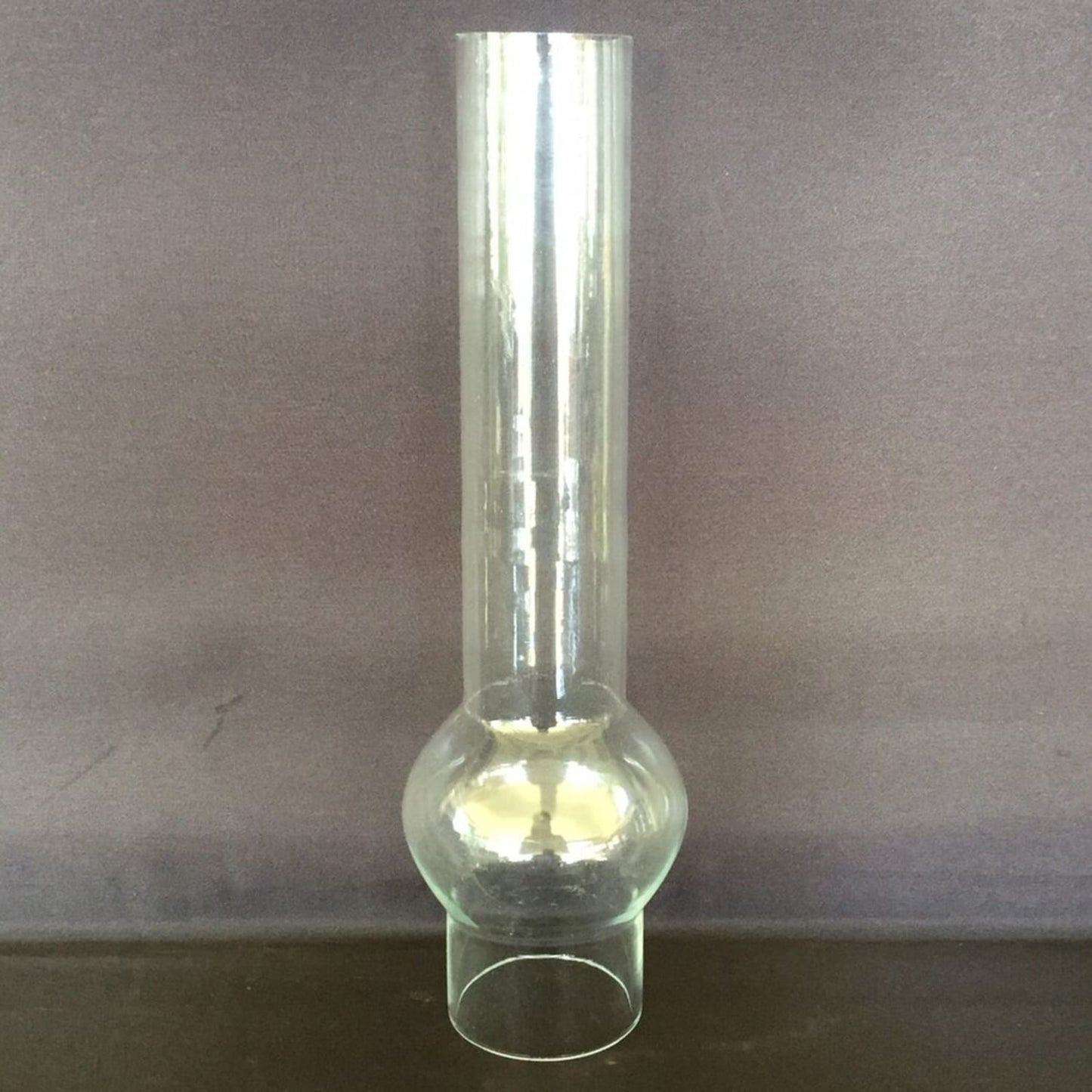 Tall clear glass chimney with a distinctive rounded bulge and narrow base, designed for oil lamps, featured in Lamps & Lighting and Parts and Accessories collections.