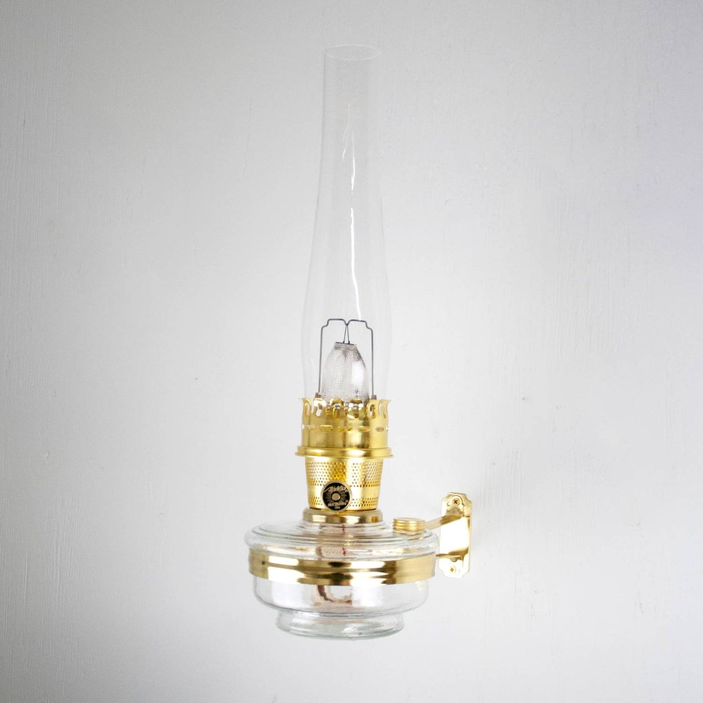 Clear glass and brass oil lamp mounted on a polished metal classic wall bracket, handcrafted for durability in Lamps & Lighting, Oil Lamps, Wall Lamps, and Best Sellers collections.
