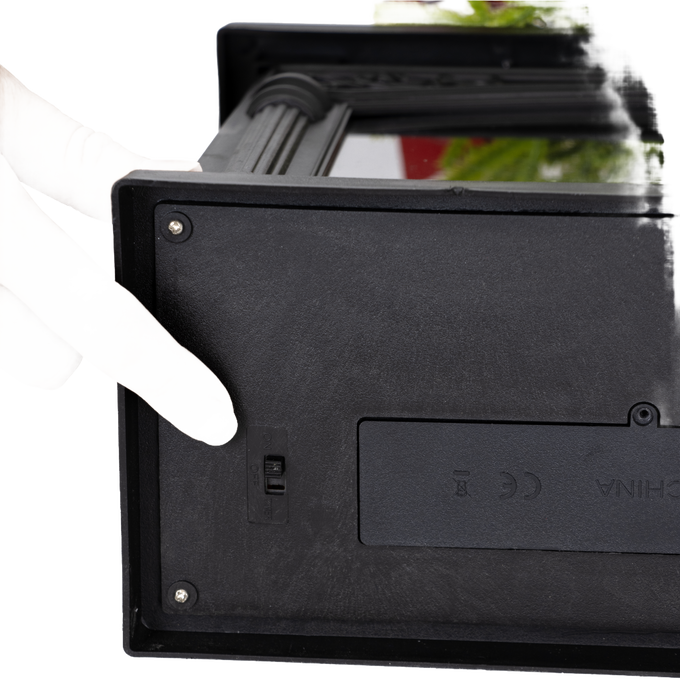 Finger adjusting the small switch on the side of a handcrafted decorative glowing fireplace, battery operated, ideal for Home & Decor, Holiday Decor, Best Sellers, and Promo Eligible collections.