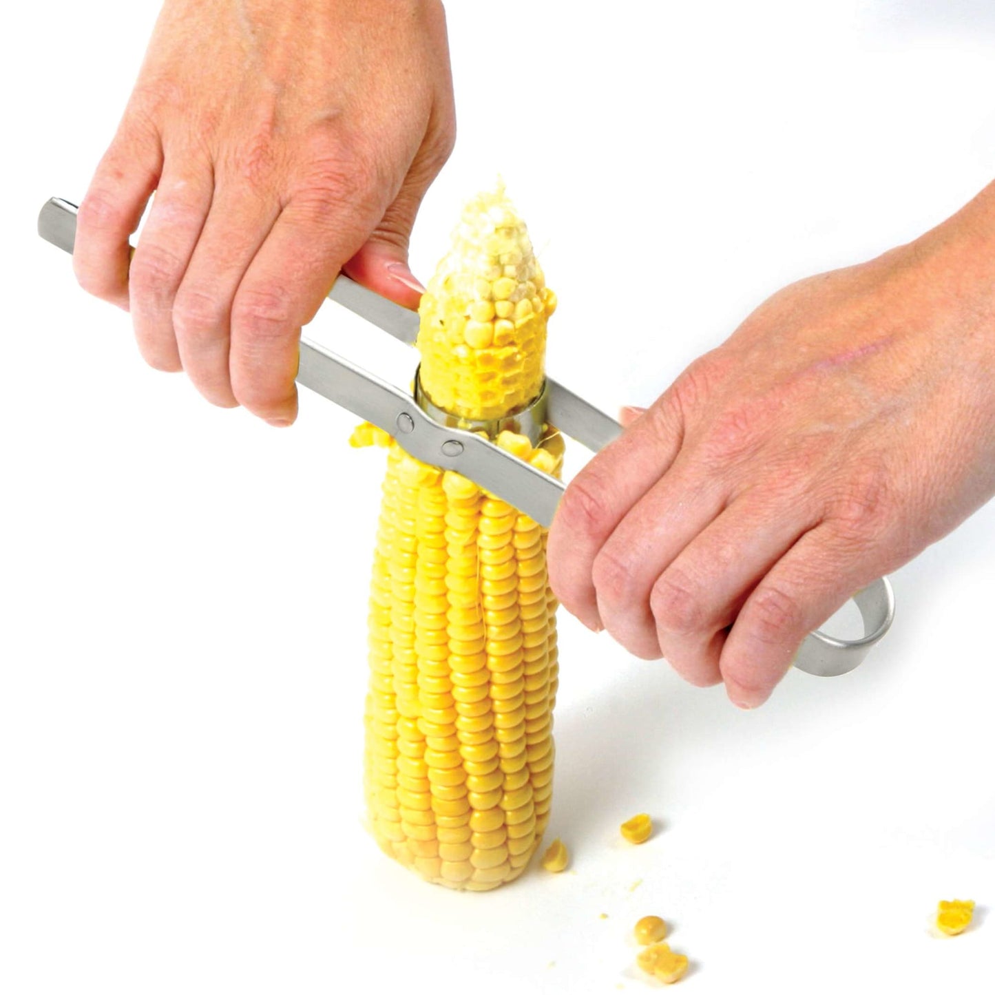 Hands using a stainless steel corn cutter to strip kernels from a fresh ear of corn, shown in a bright Kitchen & Food setting ideal for food prep and choppers collections.