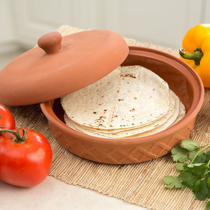 Handcrafted terra cotta tortilla warmer with glazed interior and textured exterior, keeping tortillas warm and moist, displayed with fresh tomatoes, yellow bell pepper, and cilantro, featured in Kitchen & Food, Storage and Serving, Best Sellers, and Promo Eligible collections.
