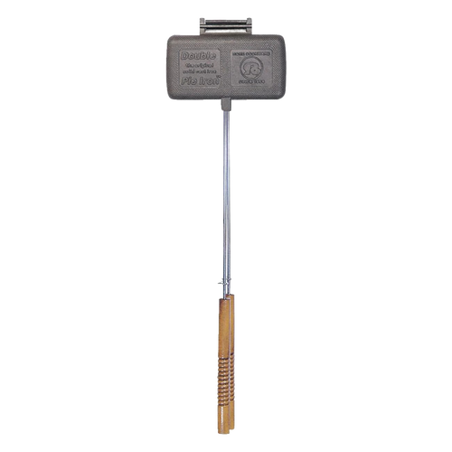 Double-compartment cast iron pie iron with long steel handle and wooden grip, handcrafted for camping and farm tool collections, designed for easy cleaning and durable outdoor cooking.