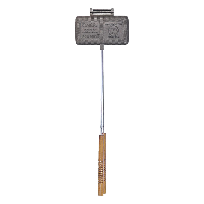 Double-compartment cast iron pie iron with long steel handle and wooden grip, handcrafted for camping and farm tool collections, designed for easy cleaning and durable outdoor cooking.