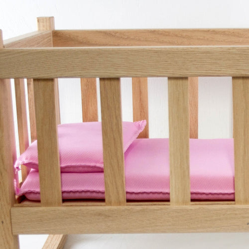 Miniature bedding set with pink pillow and mattress inside a handcrafted wooden doll cradle, highlighting Amish made quality for children's toys and doll accessories collections.