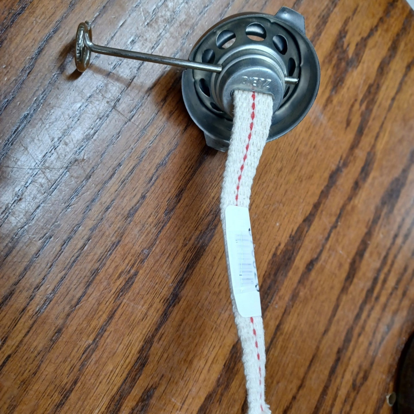 Close-up of a metal oil lantern burner with woven wick and adjustment rod, suitable for camping, emergency lighting, and lamp parts in outdoor and lighting collections.