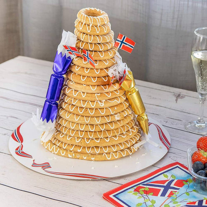 Tower of stacked ring cakes decorated with white icing and miniature Norwegian flags on a festive plate, representing a traditional Norwegian wedding cake, featured in Kitchen & Food, Cookware, Baking Supplies, Pots and Pans, Best Sellers, and Promo Eligible collections.