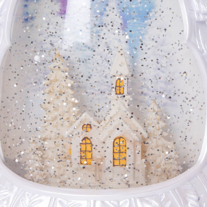 Lighted water globe featuring a snowy church scene surrounded by pine trees, creating a shimmering holiday ambiance, perfect for Home & Decor and Holiday Decor collections.
