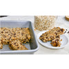 Heavy gauge seamless baking pan with oat and chocolate chip bars inside, shown alongside a plate with two bars, ideal for Kitchen & Food, Bakeware, and USA Made collections.