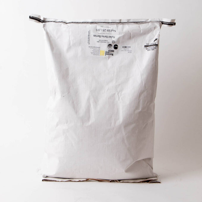 Large white paper sack with printed label containing 25 pounds of organic hulled barley groats, part of pantry, kitchen, and emergency food supplies collections.