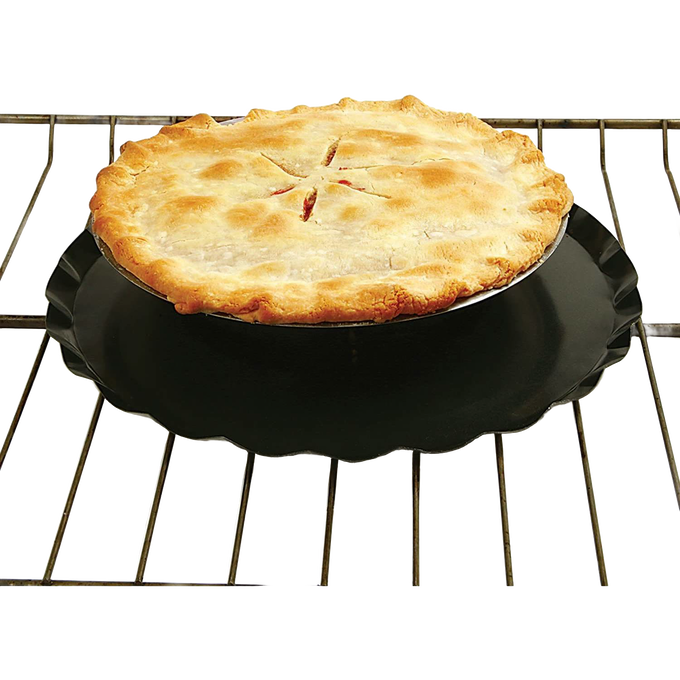 Black oven splatter guard with raised center lip and central hole for heat flow, placed on an oven rack beneath a golden-baked pie, suitable for Kitchen & Food and Kitchen Gadgets collections.