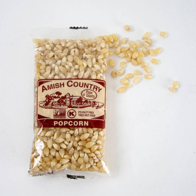 Clear plastic bag of handcrafted Amish Country popcorn kernels with a brown label, surrounded by loose yellow and white popcorn kernels, featured in Kitchen & Food and USA Made collections.