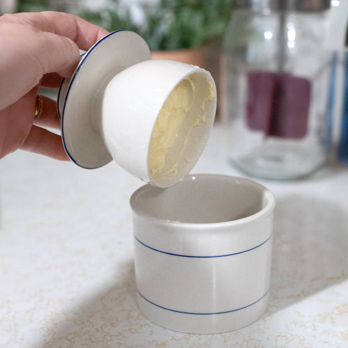 Handcrafted ceramic butter crock with simple blue line design, demonstrating butter storage by lifting the inner bowl, suitable for farm, kitchen, and homesteading collections.