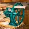 Heavy-duty cast iron grain grinder with large green wheel and wooden handle, designed for fast, fine milling in kitchen and baking supplies collections.
